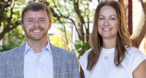 A male and female wealth advisor smiling together outside.