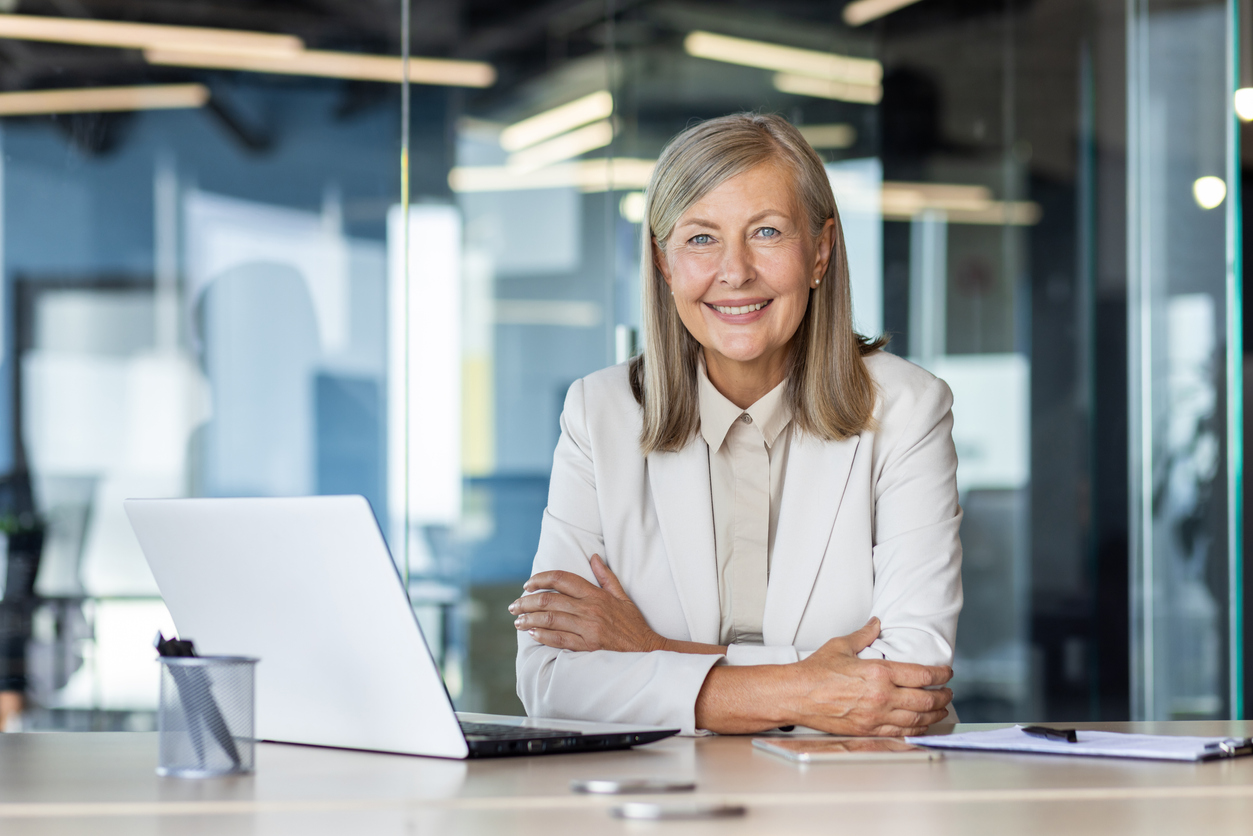 A woman sitting at a desk with a laptop smiling.