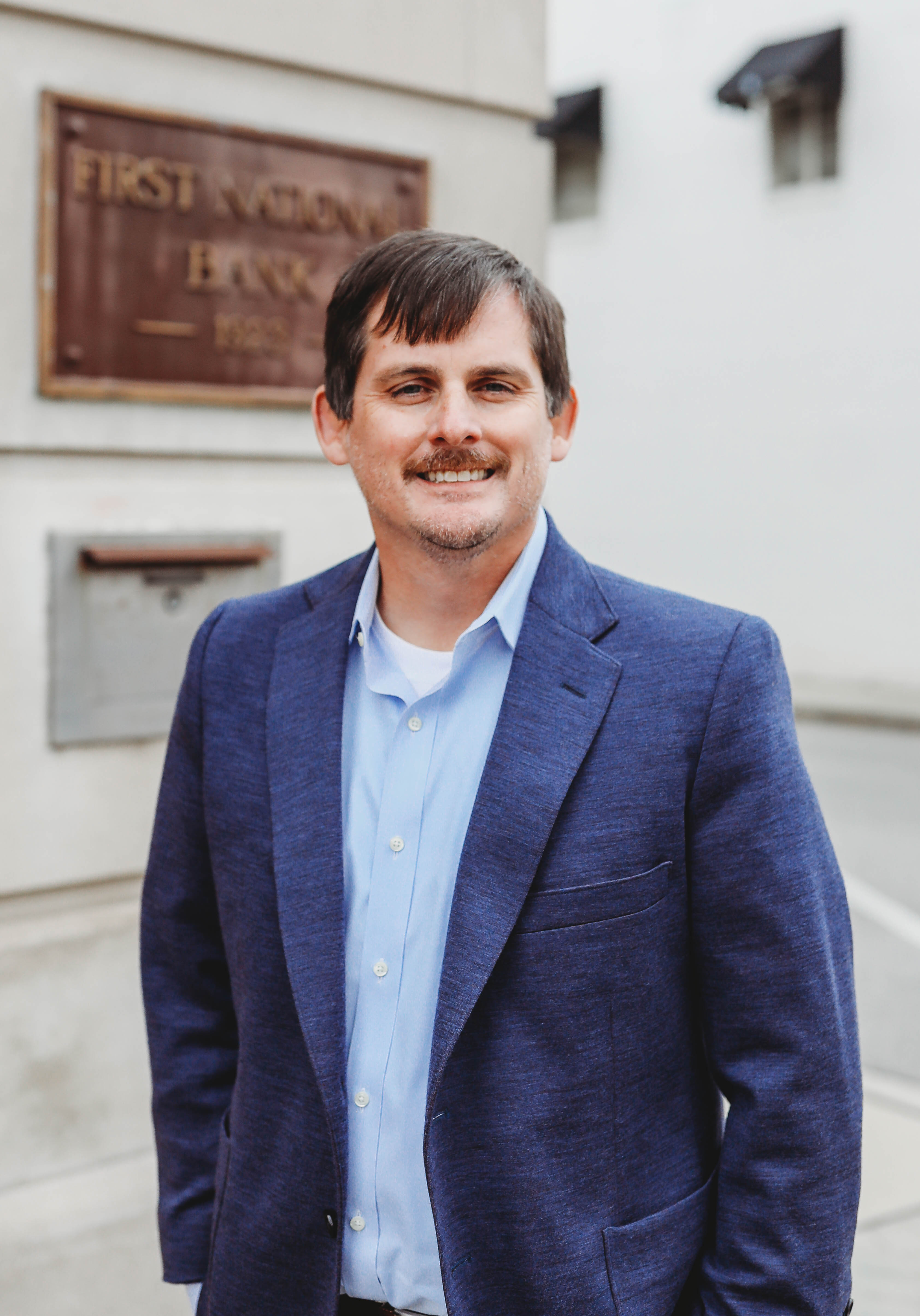 A headshot of a man standing in front of First National Bank Middle TN.