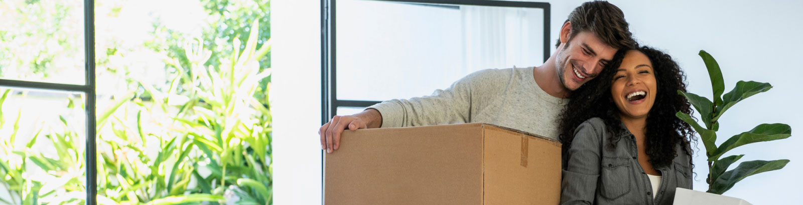 A couple laughing with each other while moving into a home.